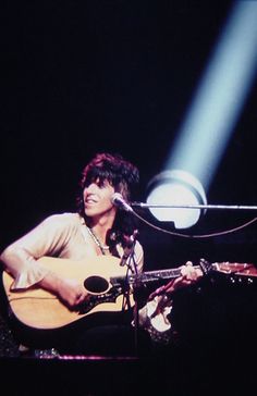 a man holding a guitar while standing in front of a microphone