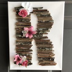 the letter h made out of sticks and flowers is displayed on a white canvas board