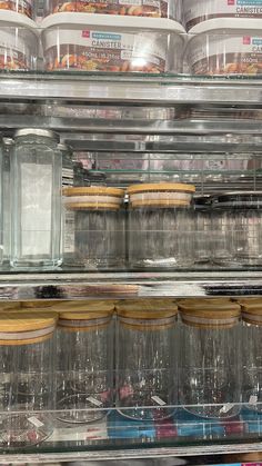 several jars and containers are stacked on top of each other in a glass display case