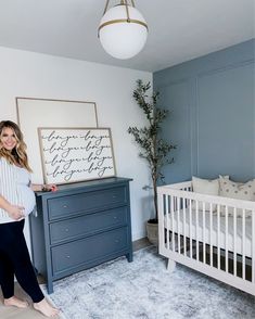 a woman standing next to a baby crib in a blue and white nursery room