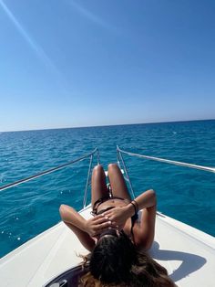 a woman laying on top of a boat in the ocean