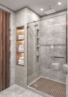 a bathroom with a walk in shower next to a wooden door and white towels on the shelves