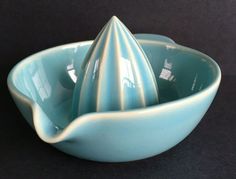 a small blue bowl with a large cone on the top in front of a black background