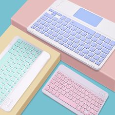 two computer keyboards sitting next to each other on top of a pink and yellow desk