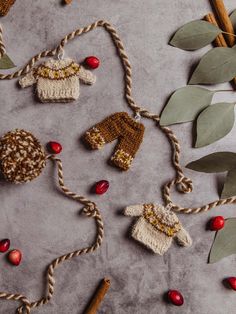 crocheted sweaters and mittens are hanging from twine on a table