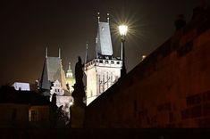 an old castle at night with its lights on and some buildings lit up in the background