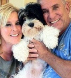 a man and woman holding a small dog