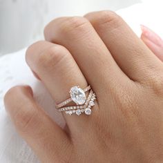 a woman's hand with a diamond ring on top of her finger and an engagement band