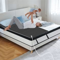 a woman laying on top of a bed holding a baby