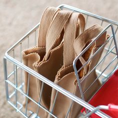 a metal basket filled with brown cloths on top of a carpeted floor next to a red chair