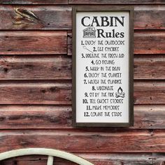 a sign on the side of a wooden building that says cabin rules next to a chair