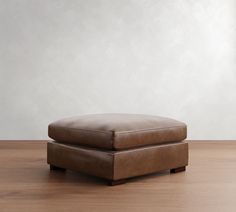 a brown ottoman sitting on top of a wooden floor