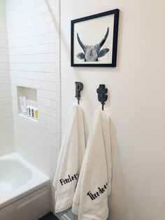 two white towels hanging on the wall in a bathroom