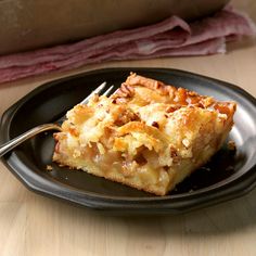 a piece of pie on a black plate with a fork