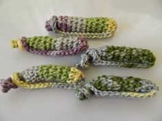 four crocheted corn cobs sitting on top of a white table next to each other