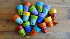 many colorful cups are arranged on a wooden surface with a butterfly flying over them,