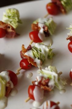 many different types of food are arranged on a white surface with bacon, lettuce and cherry tomatoes