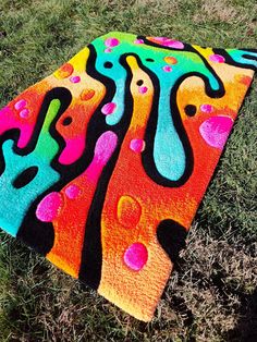 a colorful towel is laying on the ground in the grass and it looks like an abstract painting