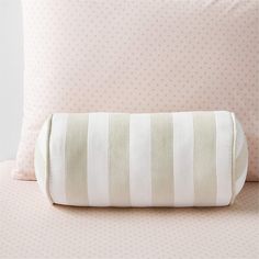 a white and beige striped pillow on top of a pink bedspread with polka dots