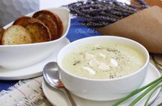 there is a bowl of soup on the plate with bread and lavenders in the background