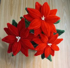 three red flowers sitting on top of a wooden table