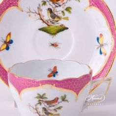 an ornately decorated tea cup and saucer with birds on the rim, is shown