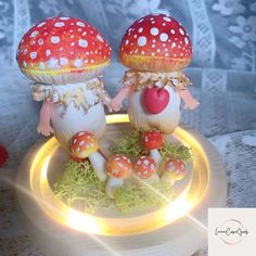 two mushrooms with hearts on their heads are sitting on a plate, surrounded by moss