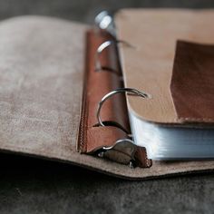 a brown leather binder with two metal clips on it and a book open to show the pages