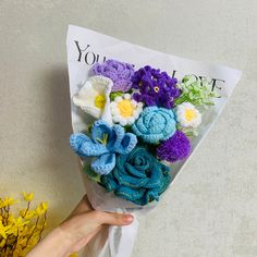 a hand holding a bouquet of crocheted flowers