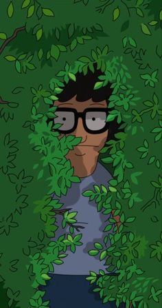 a man with glasses is hiding in the bushes