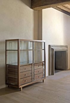 an empty room with a glass cabinet and fireplace in the corner, next to it is a fire place