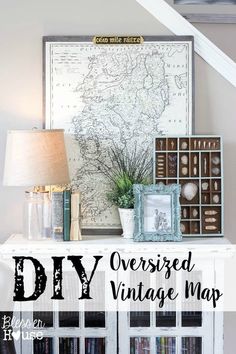 an old map is displayed on top of a white cabinet with books and vases