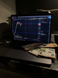 a laptop computer sitting on top of a desk next to stacks of money and euro notes