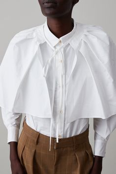 Our take on a classic, slightly oversized, button-down shirt. Full-length sleeves and six buttons down the front and two buttons at the cuff. Our Alice shirt has a petite boyish collar for a more charming take on a tailored shirt. Features detachable pleated capelet that ties at the neck. FINAL SALE Band Collar Shirt, Collar Shirts Women, Hmong Clothes, Collard Shirt, Banded Collar Shirts, Knit Outerwear, Jumpsuit Jacket, Summer Stripes, Kentucky Derby