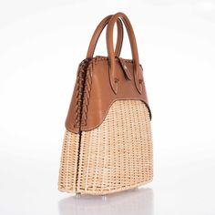 This Hermes Picnic Bolide, crafted in 2017, is an exquisite blend of rustic charm and refined elegance. This unique bag marries the natural beauty of Osier Wicker with the luxurious touch of Fauve Barenia leather, creating an accessory that is both visually stunning and tactilely inviting. The body of the bag is made from finely woven Osier Wicker, evoking the essence of serene summer days and elegant countryside escapades. This natural material adds an element of artisanal craftsmanship and giv Luxury Top Handle Straw Bag With Woven Leather, Luxury Natural Handwoven Bags, Luxury Handwoven Natural Bags, Luxury Handwoven Straw Bag With Top Handle, Luxury Handwoven Top Handle Straw Bag, Elegant Natural Woven Leather Bag, Elegant Rectangular Leather Straw Bag, Elegant Straw Bag With Bamboo Handle, Designer Shoulder Bag With Bamboo Handle In Natural Color