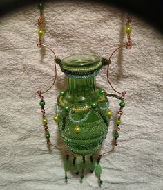 a green vase sitting on top of a white bed covered in beads and bead