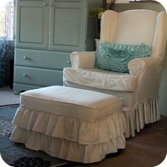 a chair and ottoman in a room with a dresser, armoire, and window