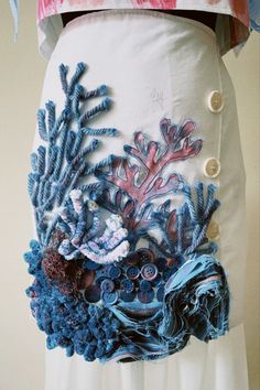 a woman's skirt made out of buttons and fabric with corals on it