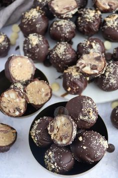 chocolate covered desserts are on black plates with white and gold sprinkles