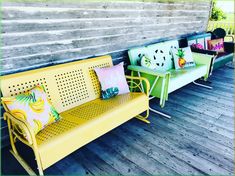 three yellow and green benches sitting on top of a wooden deck next to each other