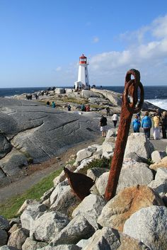 people are walking on the rocks by the lighthouse