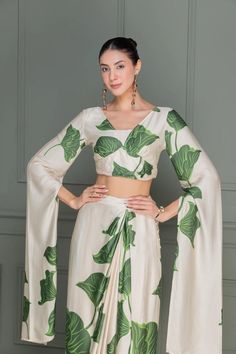 We have curated a special collection of Festive Fusion with eye-catching ensembles in the most versatile styles, with the perfect blend of Floral Prints, embellished with traditional detailing's and flattering silhouettes. Get ready to slay in our eclectic styles that can be dressed up to any wedding festivities or can be flaunted to make a statement on Sunday brunches!   Top: Viscose Floral Print  V-Neck Drape Long sleeves Back Zip  Dry Clean Only  Skirt: Viscose Overlap Dhoti Style Drape Belt Fitted Digital Print Georgette Sharara, Reception Georgette Sets With Printed Motifs, Fitted Sharara With Printed Motifs For Reception, Reception Sharara With Printed Motifs, Reception Sharara Saree With Printed Motifs, Reception Sets In Georgette With Printed Motifs, Navratri Draped Sets With Cutdana, Reception Sets With Printed Motifs In Georgette, Navratri Draped Cutdana Sets