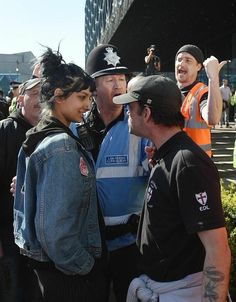 a group of people standing next to each other in front of a police officer wearing an orange vest