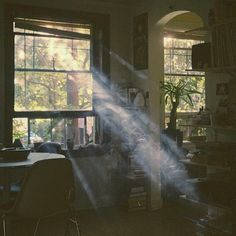 the sun shines through the window in this dark room with furniture and bookshelves