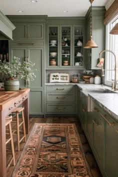 a kitchen with green cabinets and an area rug on the floor in front of it