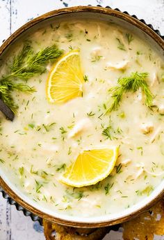 a bowl filled with lemon and dill soup next to crackers on a table