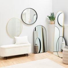 three mirrors are on the wall next to a white couch and chair with a potted plant