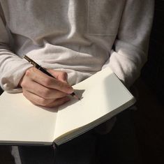 a person holding a pen and writing on a notebook