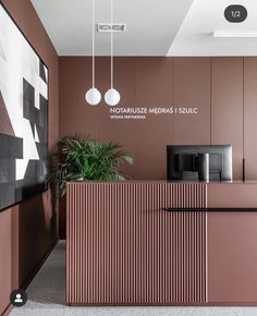 the front desk of an office with pink walls and black counter tops, along with hanging lights