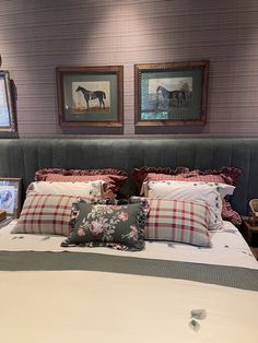 a bed with two framed horses on the wall above it